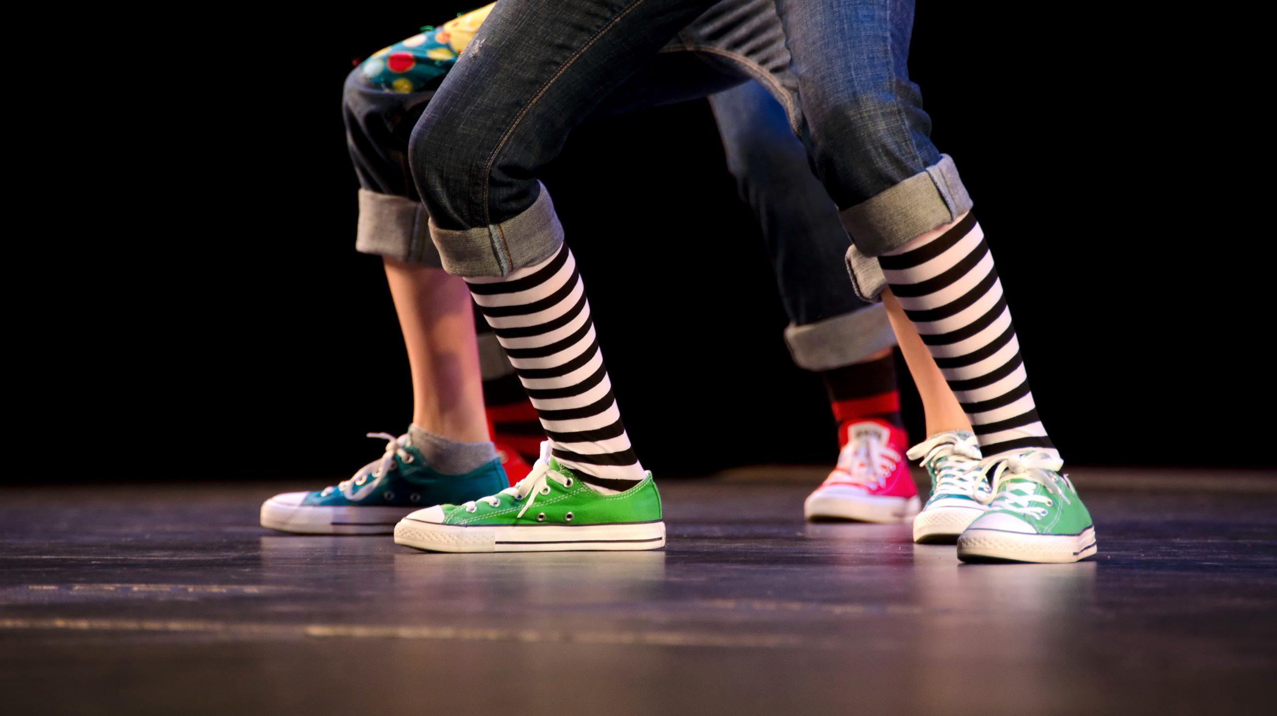 Feet of a trio of hip-hop performer in colorful sneakers